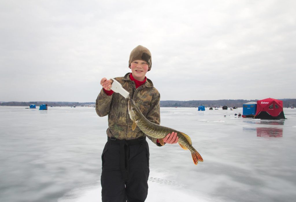 Kid holding fish caught ice fishing