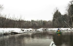 paddling on a river in winter, showing kayak and person in winter clothes