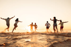 People Running into Water at Sunset