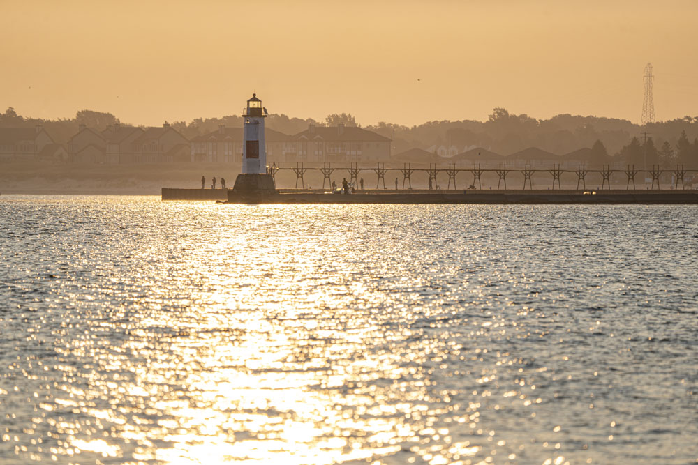 Sport fishing on Lake Michigan at Manistee, Michigan. River channel with lighthouse at sunset