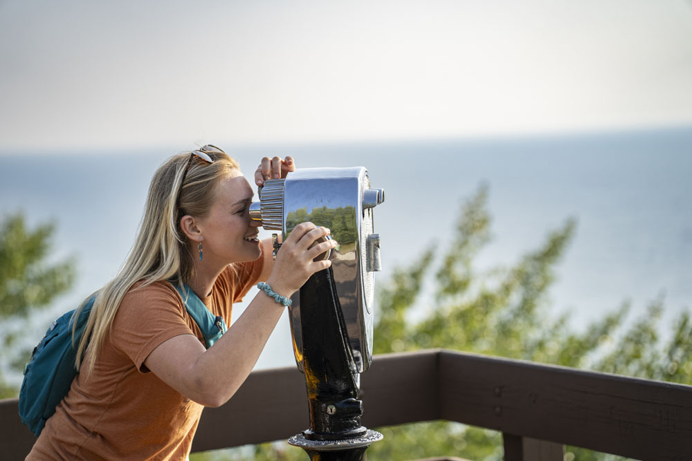 Arcadia Dunes overlook on Lake Michigan near Manistee. Woman peering through binoculars at Arcadia Overlook