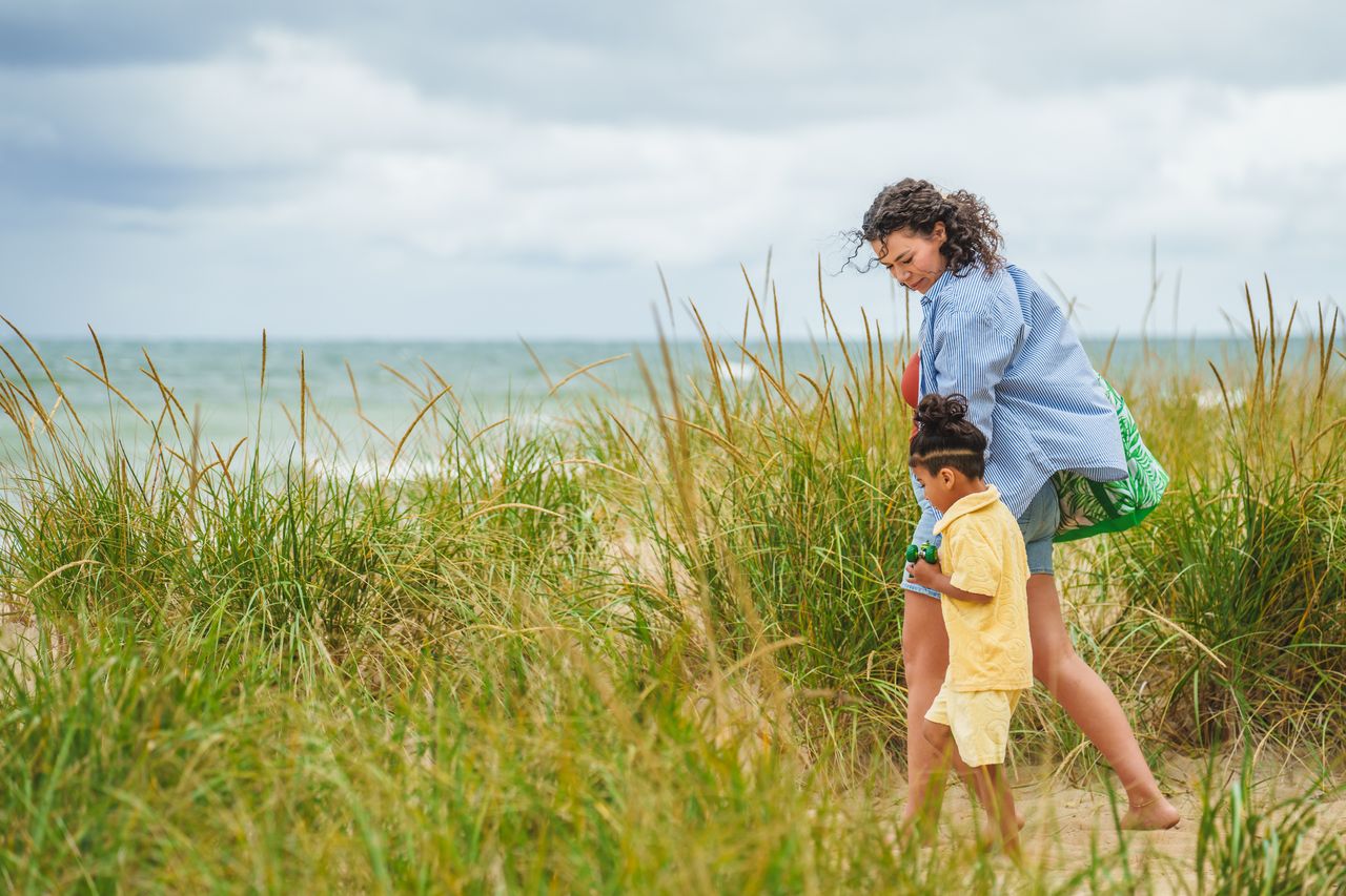 biJmxShw Mother and child walking amongst beach grass